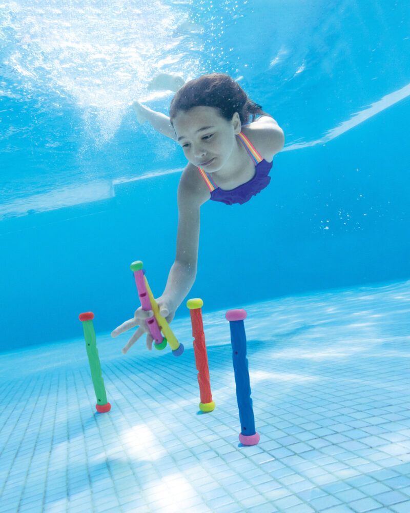 Child underwater reaching for colorful diving sticks in a pool, illustrating fun pool accessories for kids.