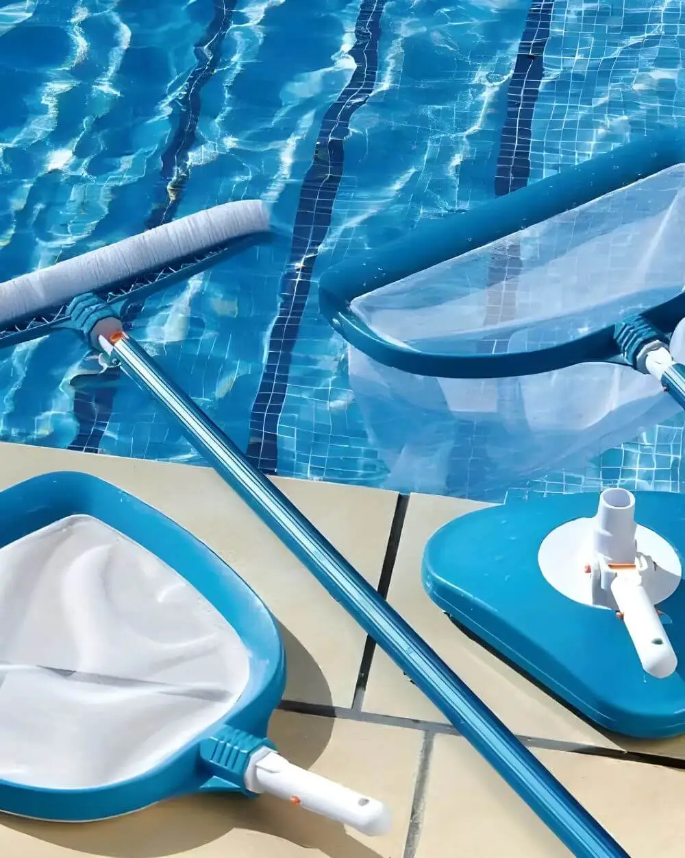Pool cleaning supplies including a skimmer net, vacuum head, and cleaning pole on the edge of a swimming pool, highlighting maintenance tools for effective pool care.