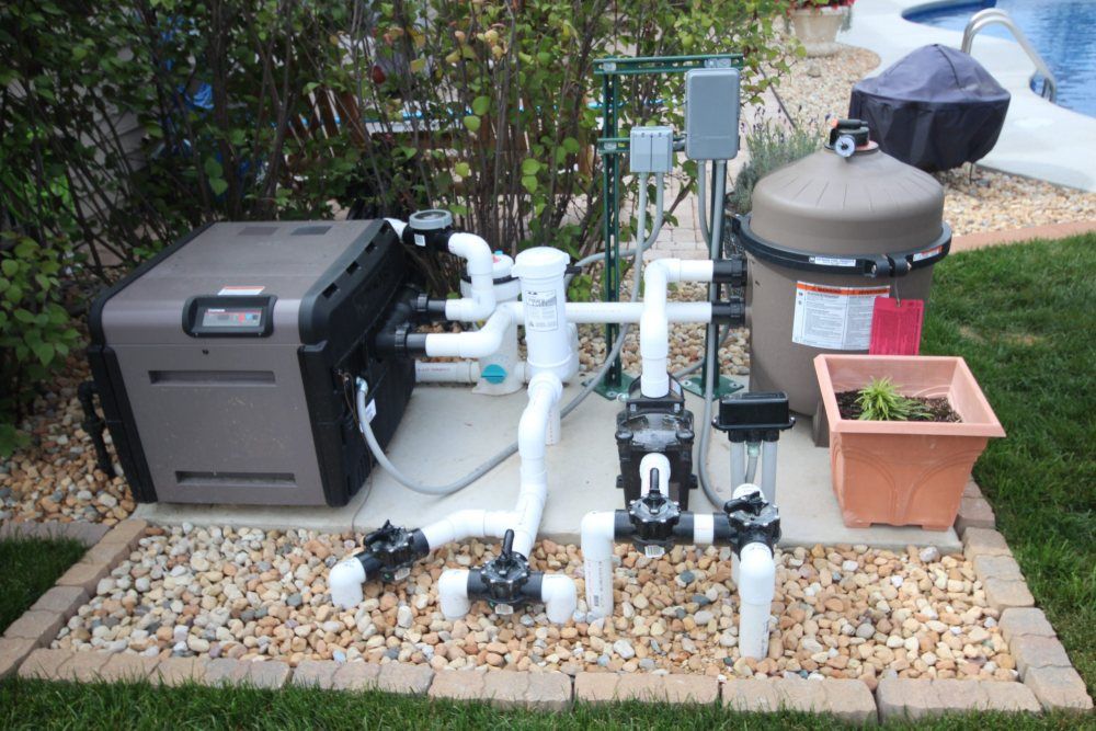 Pool equipment setup featuring a pump, filter, and plumbing, essential for maintaining clean and safe water quality in residential pools.
