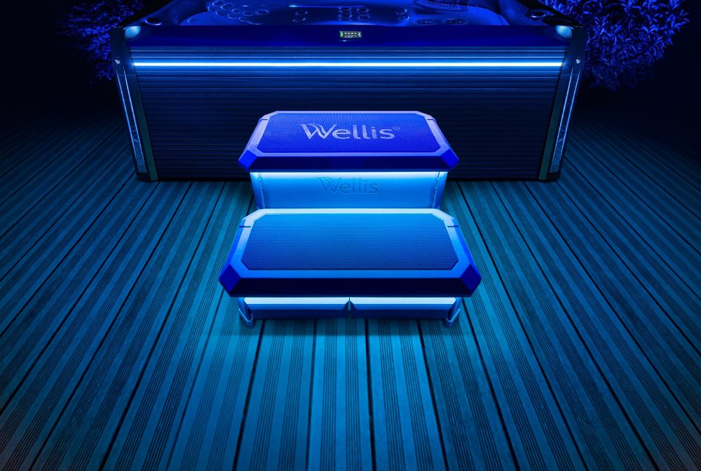 Wellis spa steps illuminated at night, showcasing modern design and ambiance, with a spa in the background, highlighting pool and spa maintenance services.