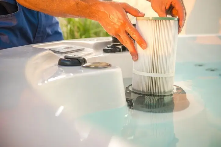 Hands removing a spa filter from water, demonstrating deep filter cleaning service for improved water clarity and circulation.