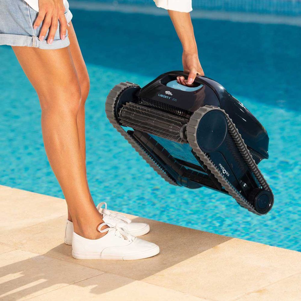 Person holding a pool cleaning robot above a swimming pool, showcasing outdoor maintenance equipment for leisure spaces.