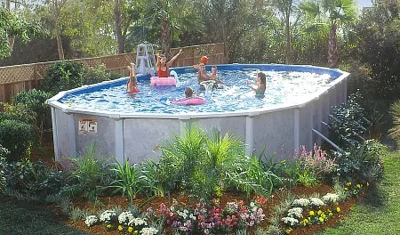 Group of people enjoying a swim in an above-ground pool surrounded by tropical plants.