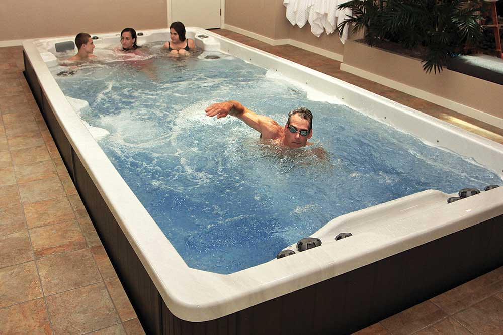 Swim spa with four people enjoying hydrotherapy and exercise, showcasing the Wellis SwimLine features for relaxation and fitness.