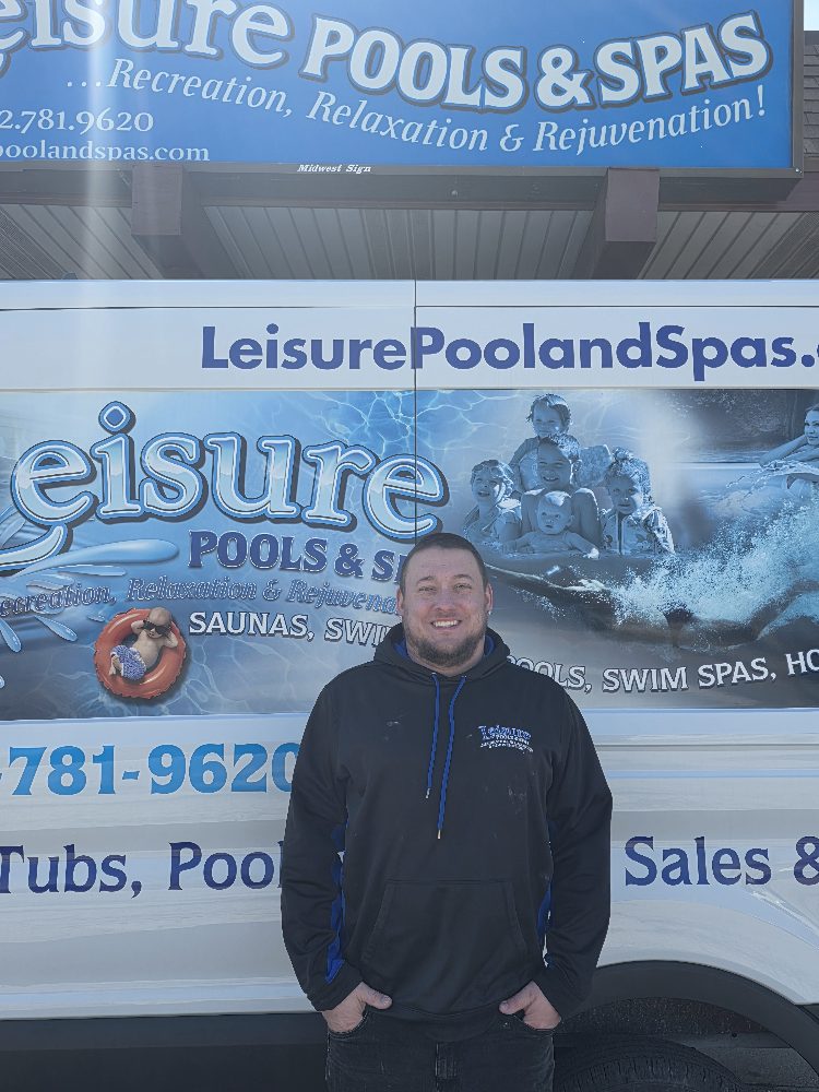 Service manager Andy Reed standing in front of Leisure Pools & Spas vehicle, showcasing company branding and services for pools and hot tubs.