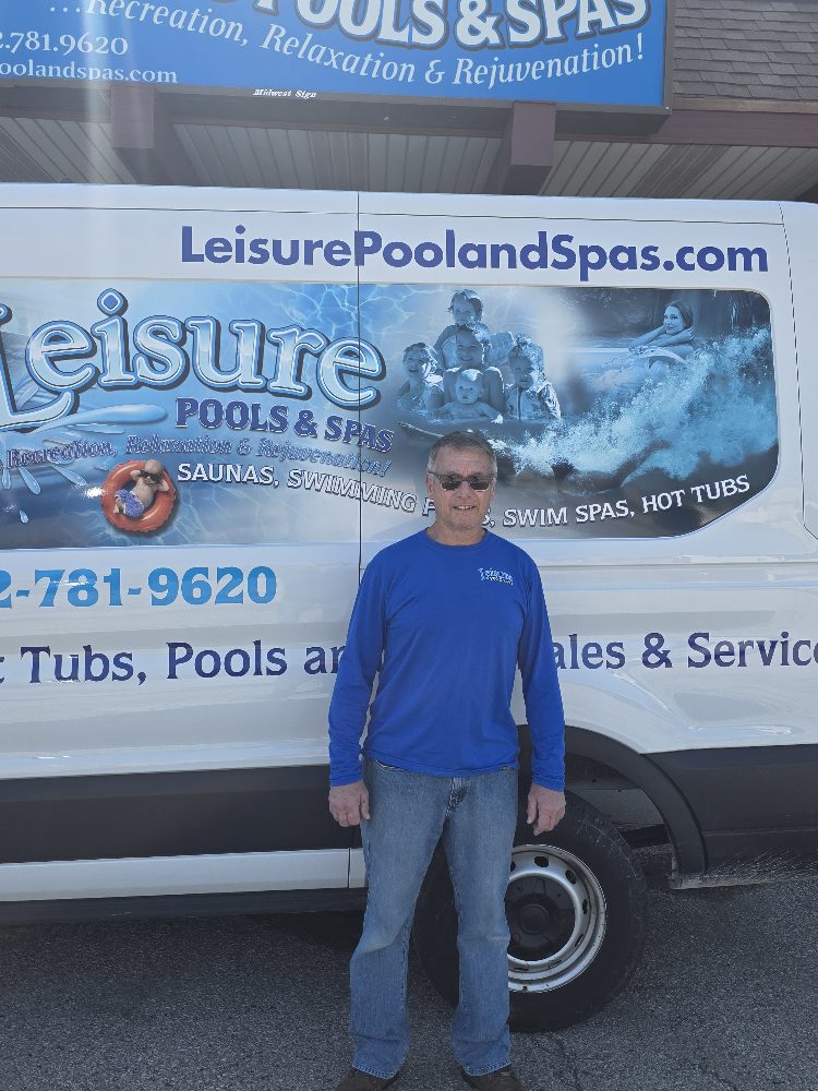 Man in blue shirt standing in front of Leisure Pools & Spas service van, showcasing company branding and contact information for pool and hot tub services in Brookfield.