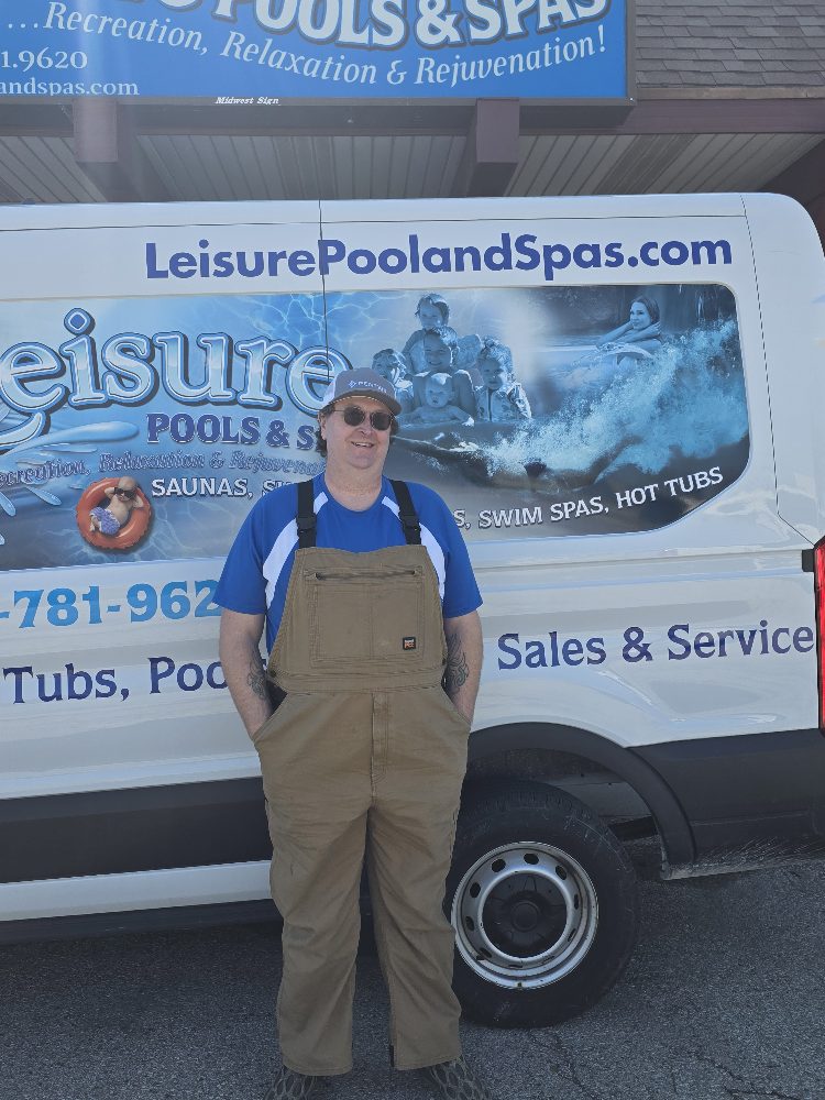 Service technician in overalls standing in front of a Leisure Pools & Spas vehicle, showcasing the company's branding and services for pools and hot tubs.