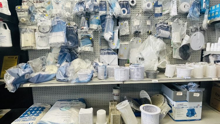 Assorted pool and spa supplies including filters, pumps, and accessories displayed on shelves at Leisure Pools & Spas store.