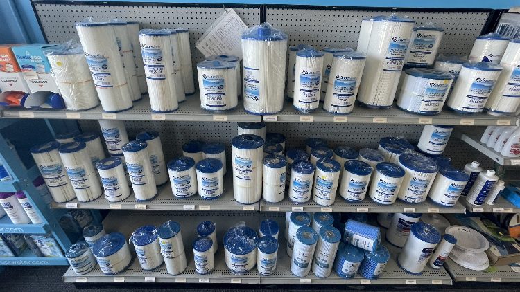 Shelves stocked with various pool and spa filter cartridges and accessories at Leisure Pools & Spas store.